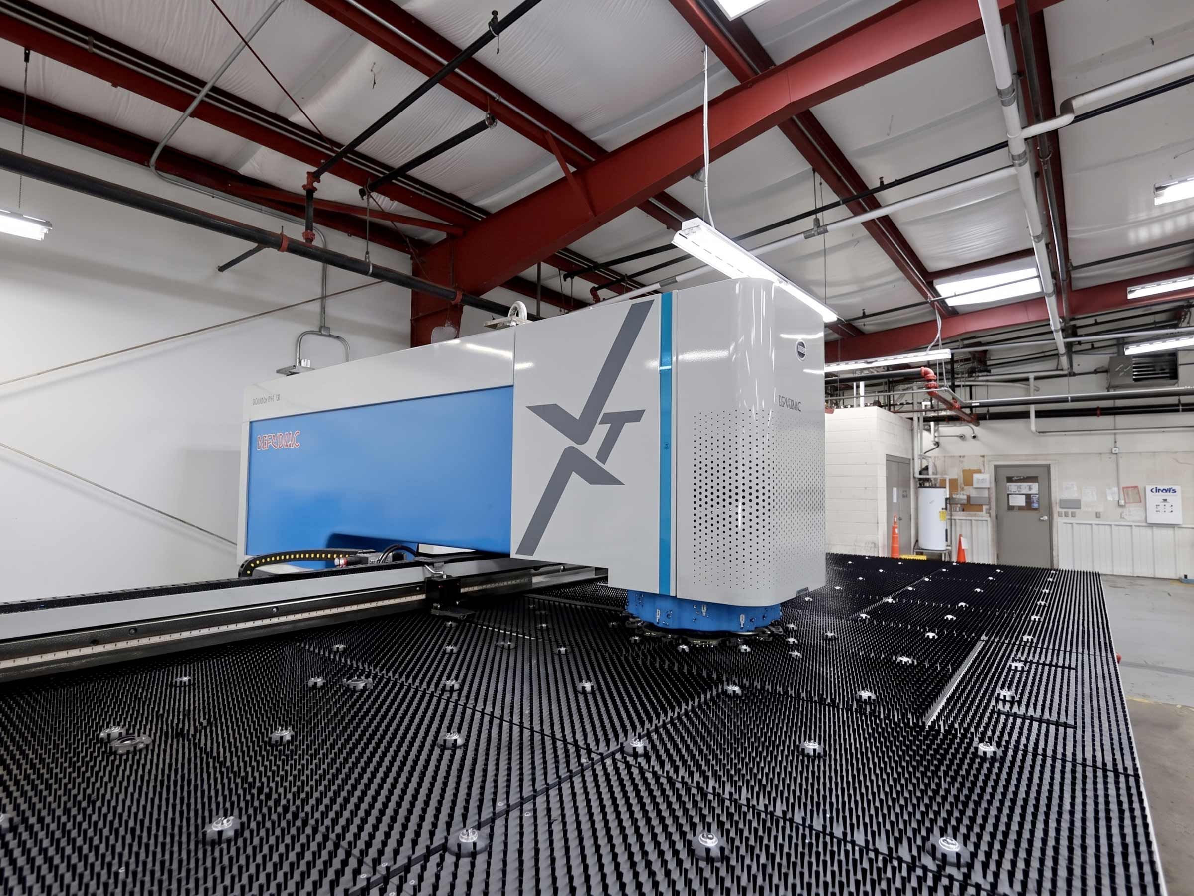 A CNC sheet-metal fabrication machine and its slatted cutting bed on the Heritage Metal Products shop floor in Raleigh, NC